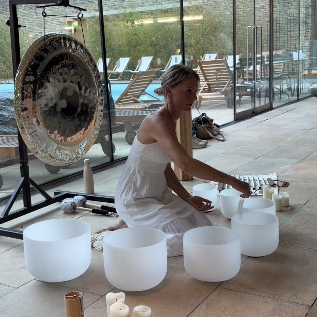 Crystal singing bowls and a gong played at the water's edge during an evening floating sound bath